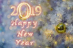 2019年新年快乐写的火花烟花在圣诞树的背景与抽象模糊散景，庆祝和贺卡2019概念