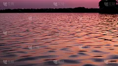 海浪在夕阳西下的海面上。阳光下平静的水面。日落在黄昏的湖面上。