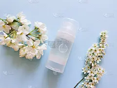 模拟透明瓶的亲密润滑剂凝胶。蓝色底色，白色花朵。贴心的按摩，舒适的性爱。生活方式，平躺，俯视图