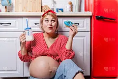 孕妇抱着甜甜圈。孕期体重控制和不健康饮食的概念