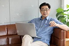 亚洲人使用笔记本电脑在网上购物和支付信用卡