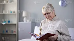 伤心的戴着眼镜的老妪在家里看着相册，思念着家人