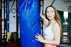 迷人的年轻女子向蓝色沙袋打了一拳