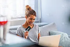 年轻漂亮的女人高兴地寻找购物物品在网上出售。网上购物的概念。在家网购的快乐女人