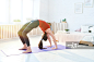 Flexible young woman performing wheel pose while practicing yoga on mat in bedroom_创意图片