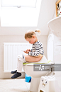 Little girl with smartphone sitting on the toilet._创意图片