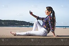 一名年轻女子在海滩边用手机自拍