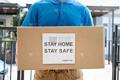 快递服务男性身着制服给客户前台送纸箱包裹到客户家，快速快递异地时危机冠状病毒，新冠肺炎新常态生活理念