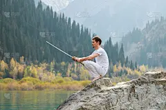 一个拿着剑的人坐在一块响亮的石头上。锋利的刀片。