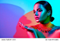 High Fashion model woman portrait in colorful bright neon lights, beautiful party girl with trendy make-up, manicure, haircut. Pointing hand, advertising gesture over colourful vivid background