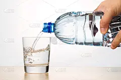 用手将清爽的天然矿泉水从瓶中倒入玻璃杯中