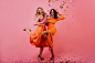 Fulllength portrait of two girls dancing under confetti studio photo of american women enjoying event