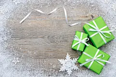 木质表面上有蝴蝶结和雪花的绿色礼品盒
