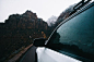 White vehicle driving down a mountain road in a driver's side POV.