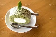 一块绿茶饼卷，里面为喝茶时间抹上白奶油放在木桌上