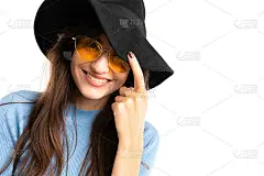 年轻的女孩带着愉快的微笑，栗色的长发，漂亮的妆容，蓝色的运动衫，黑色的牛仔裤，灰色的贝雷帽，眼镜，黑