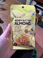 a person holding up a bag of honey butter almonds in front of a wooden table