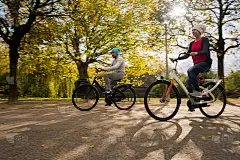 快乐的年轻情侣在阳光明媚的秋日骑自行车在大自然中。