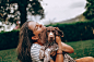 woman in white and black stripe tank top hugging brown and white short coated dog