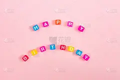 用彩色的立方珠串上字母，写上生日快乐。节日的粉红色背景概念与复制空间