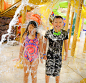 A boy in black swim wear and a girl in a colorful bathing suit gets soaked under the tipping bucket at Great Wolf Lodge 