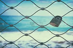 生锈的老锁上的铁栅栏与蓝色的海洋背景。
