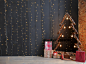 圣诞新年室内与黑色的墙壁背景花环，冷杉树与灯和圣诞礼物