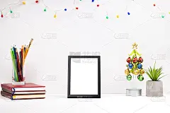 办公室或家庭工作场所模型。模板圣诞贺卡。白色的桌面和空白的框架。文具和圣诞装饰品在桌面。侧视图
