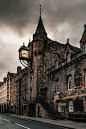 an old stone building with a clock on the front and stairs leading up to it