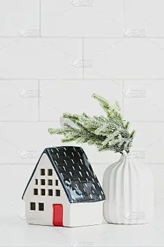 北欧圣诞家居装饰。小陶瓷房子和杉木枝花瓶。舒适的家，hygge，斯堪的纳维亚风格。