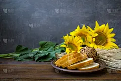 秋收，自然物产，贺卡理念。静物画有美丽的向日葵，切片的白面包，木制的乡村背景上的小麦小穗。