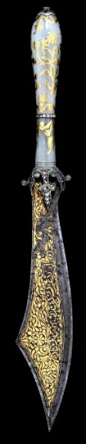 AN OTTOMAN JADE-HANDLED COURT DAGGER   19TH CENTURY   With shaped single-edged blade with curved cutting edge and bold clip-point, each side of the blade with gold-damascened flowering foliage framing an inscription, small ornate silver guard set with cle