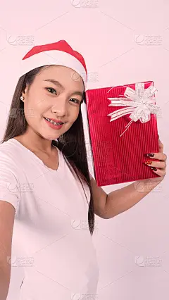 女孩拿着礼盒自拍或网上视频与圣诞道具装饰。亚洲泰国少女与她的朋友在红礼盒网上自拍庆祝节日季节。影棚拍