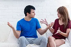 不幸福的夫妇在家。帅哥和美女一起坐在白色的沙发上。丈夫的态度很烦妻子抱怨他。关系概念中的几个问题。
