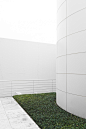 A small lawn in a white concrete courtyard