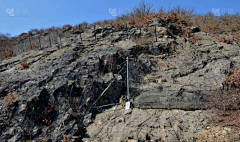 用深嵌在岩石中的钢网加固斜坡。排成倾斜的栅栏，在山口上方有巨大的网状物，将挡住侵蚀的大石头和坠落的石