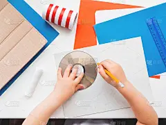 孩子用彩纸、厕纸芯、纸箱、剪刀、胶水、cd盘、铅笔和尺子做东西。红、白、蓝调色板。用临时材料制作玩具