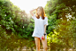 selective focus photo of woman standing behind green trees