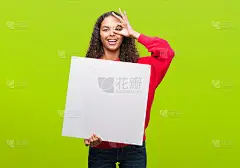 年轻的西班牙妇女拿着空白旗帜与快乐的脸微笑做ok手势与手在眼睛透过手指看
