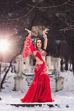 美丽的年轻女孩跳舞肚皮舞在冬天在一个公园的雪地上。