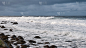 白色的浪花在白茫茫的大海的岩石海岸上翻滚。戏剧性的天空，史诗般的海景。海上的风暴。北欧，巴伦支海，海