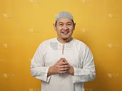 肖像快乐的年轻亚洲穆斯林男子微笑和摆姿势的相机，对黄色