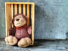 可爱的猴子微笑娃娃坐在水泥背景的木箱上。给你特别的一个惊喜礼物。复制空间和复古风格