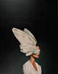 This may contain: a woman with white feathers on her head is standing in front of a black background