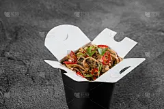 炒锅内装麻辣面条，装在黑色食物容器中。快餐外卖服务。中餐的外卖。