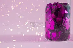 紫色的心形玻璃瓶子在粉红色的背景与复制空间和模糊灯光散焦，散焦。节日概念为您的创意设计