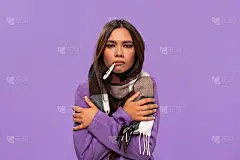 漂亮的非洲裔美国女孩在一件毛衣和舒适的格子围巾检查温度计站在孤立的紫色背景。冬天感冒。