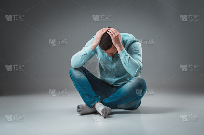 一个沮丧的年轻人双手抱头坐着