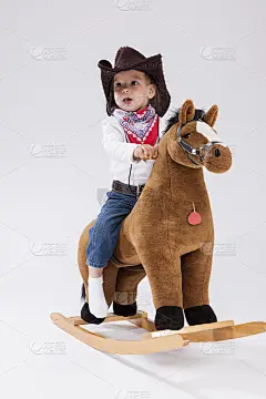 小孩子Consepts。微笑快乐的小白人女孩在牛仔女服装摆姿势的象征马对白色。垂直的形象定位