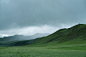 A green field with mountains in the background